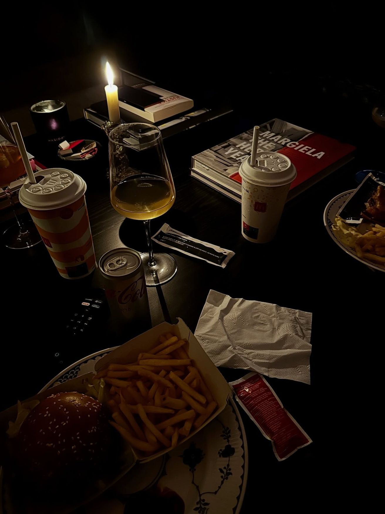 Candlelit table after hours with wine, fries and art books