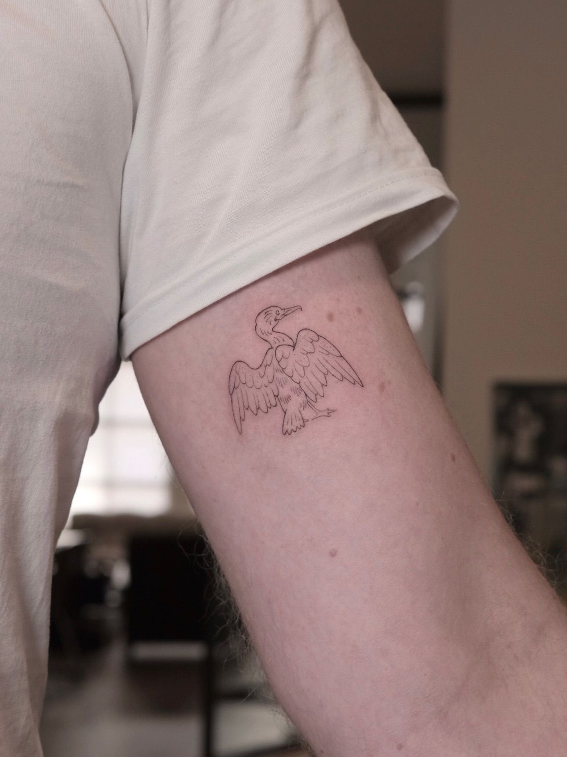 Small eagle with spread wings on the upper arm